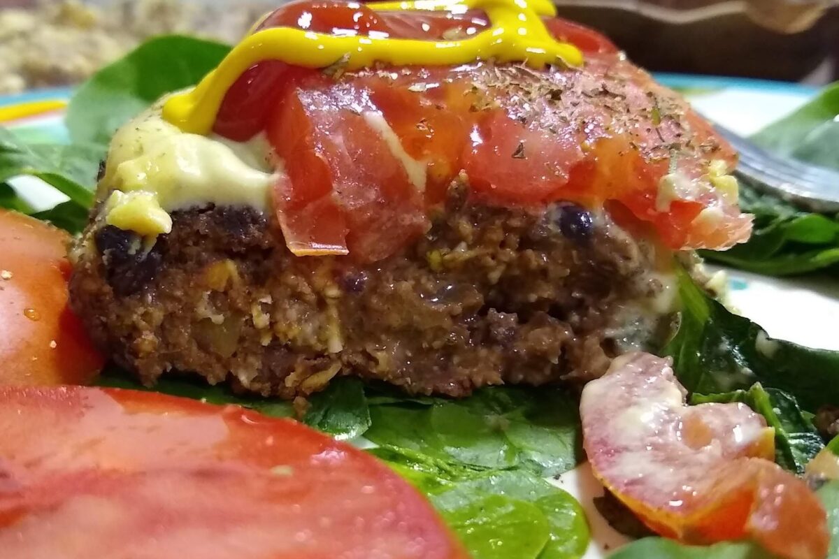 veggie burger on a bed of spinach with tomatoe and mustard on top