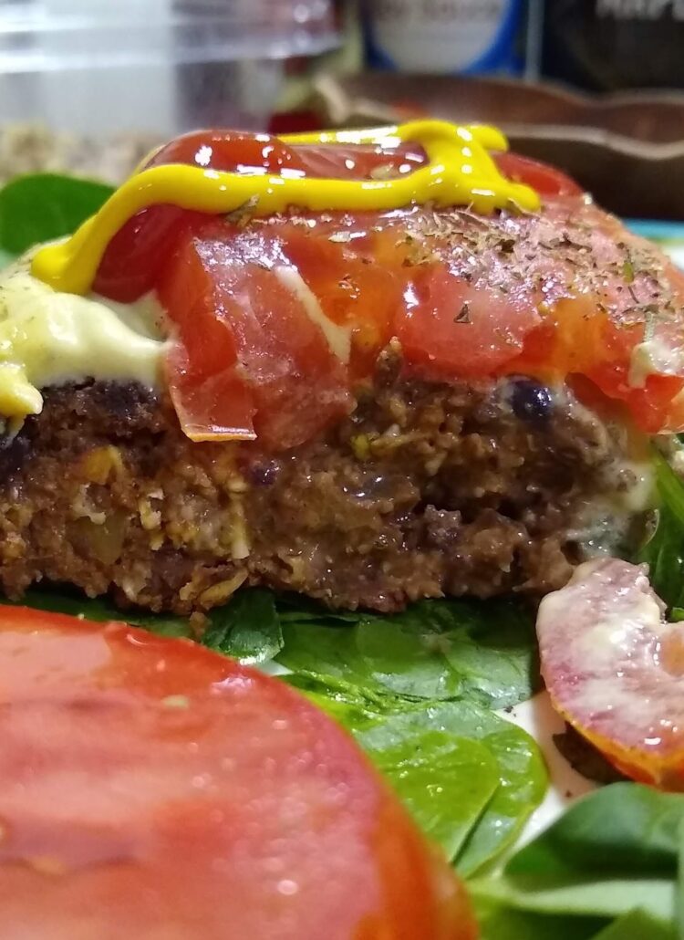 veggie burger on a bed of spinach with tomatoe and mustard on top