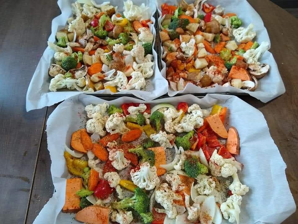Three parchment paper lined cooking sheets filled with brightly colored vegetables