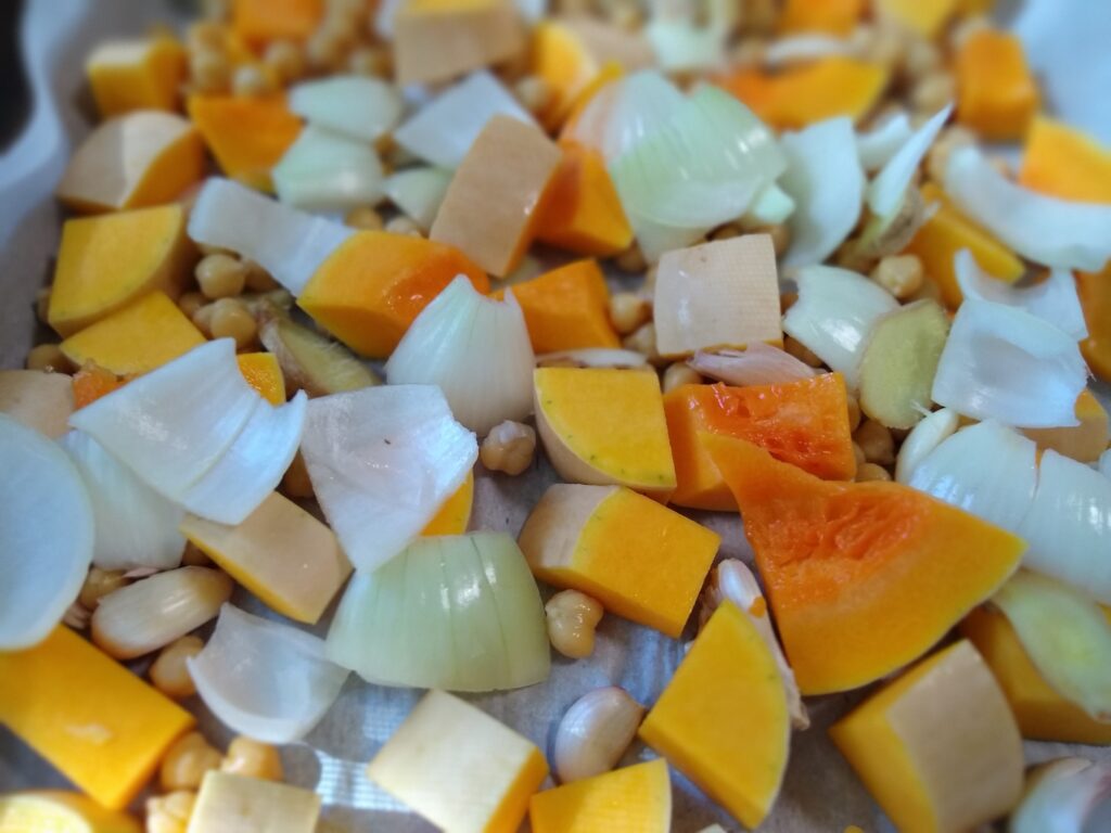 Roasted butternut squash, chickpeas, garlic, onions and ginger on a parchment paper lined baking sheet 