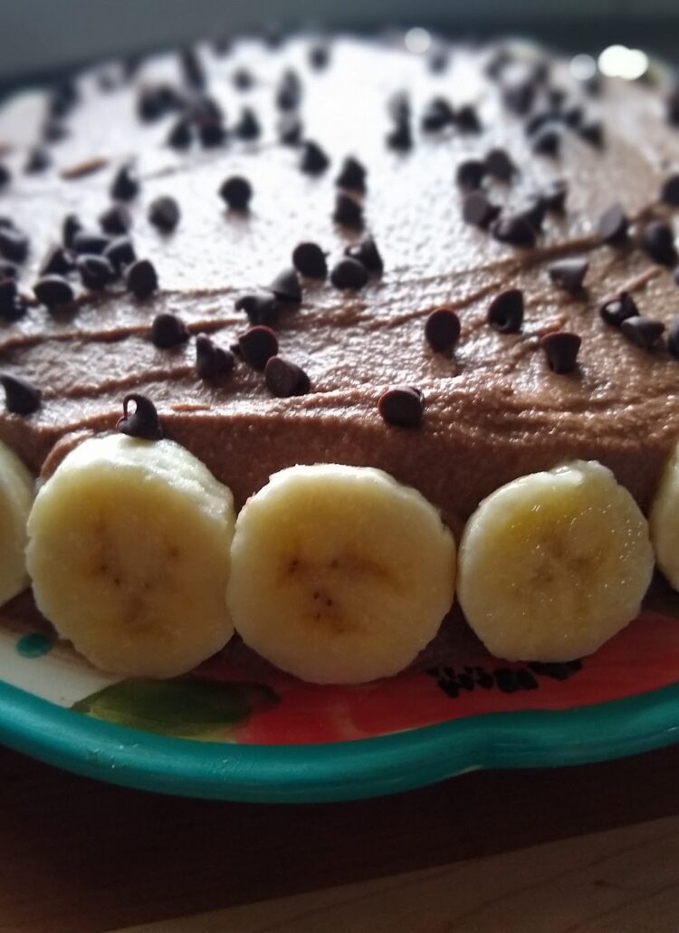 Beautiful yellow cake with chocolate frosting on top and banan slices on the side