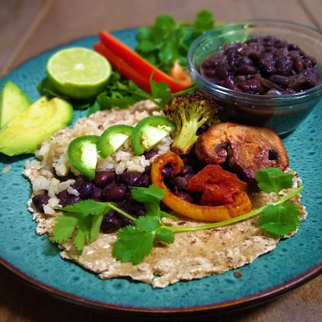 Fabulously fresh fajittas on a oat flour tortilla with slices of crisp jalapenos, fresh squeezed lime, cilantro and bell pepper slices with a side of black beans and avocado